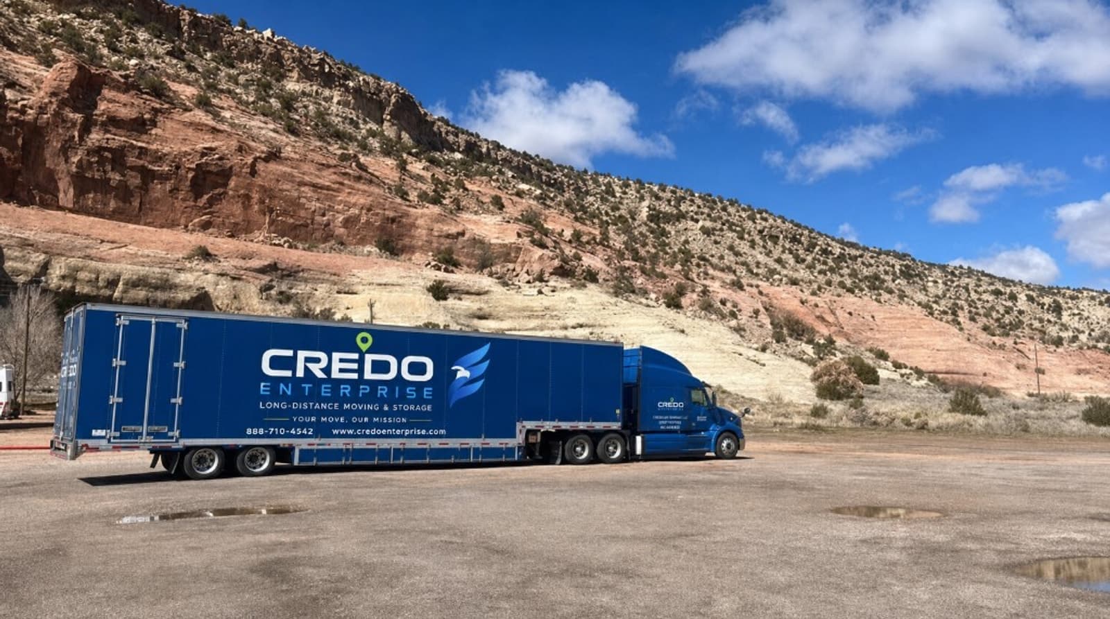 Credo Enterprise long-distance moving truck with branded trailer in a desert landscape