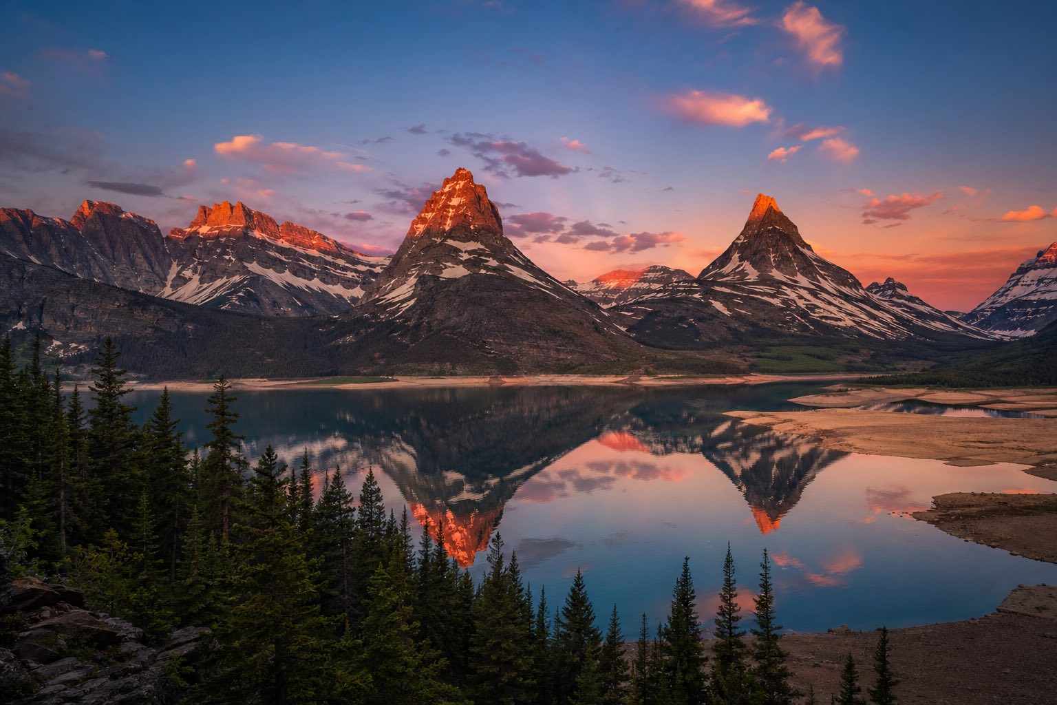Modern photograph of Glacier National Park alpine peaks reflected at sunset representing Credo Enterprise' Montana service area